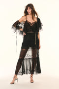 Woman wearing a black lace dress with sheer panels on a white background