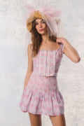 Woman wearing a floral dress and straw hat against a light background