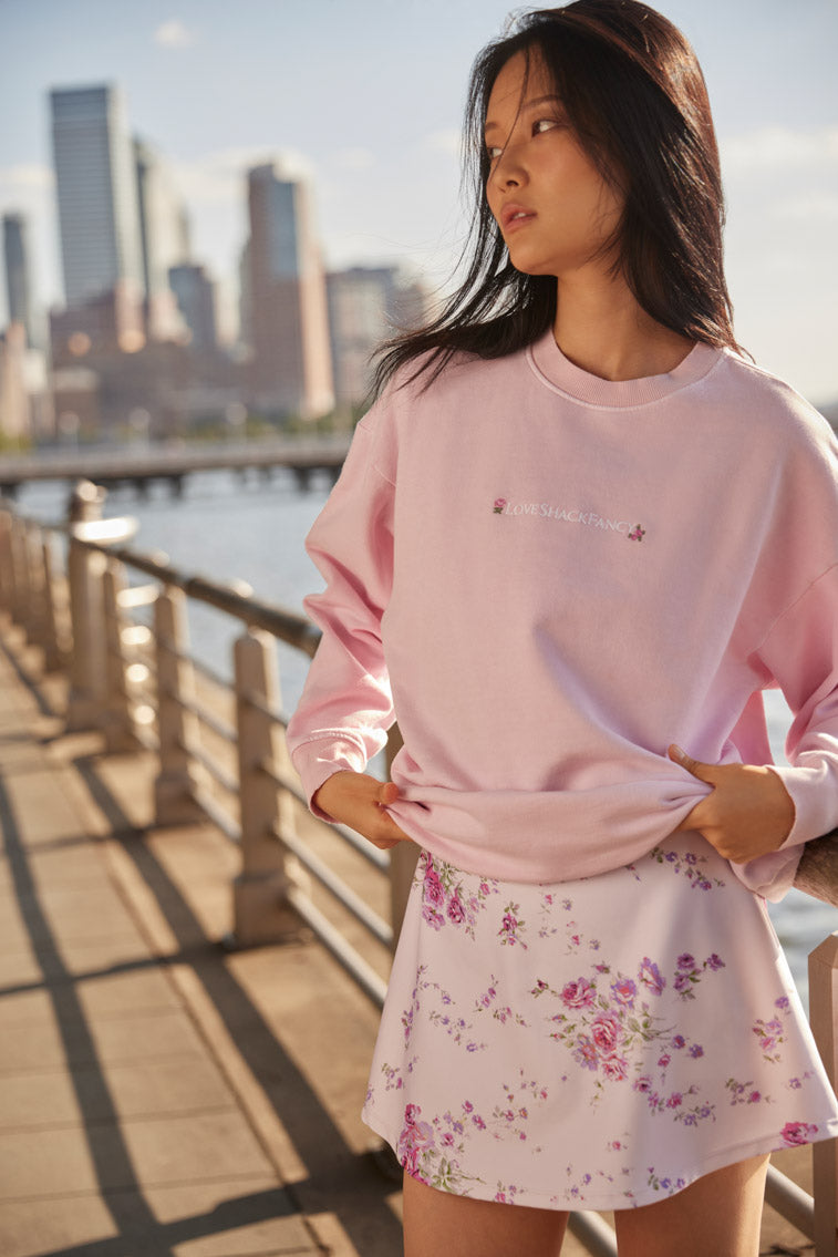 light pink Crewneck pullover sweater with embroidered flowers near the neckline and LSF logo at the sleeve cuff