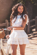 Woman in a white set standing next to a bicycle outdoors
