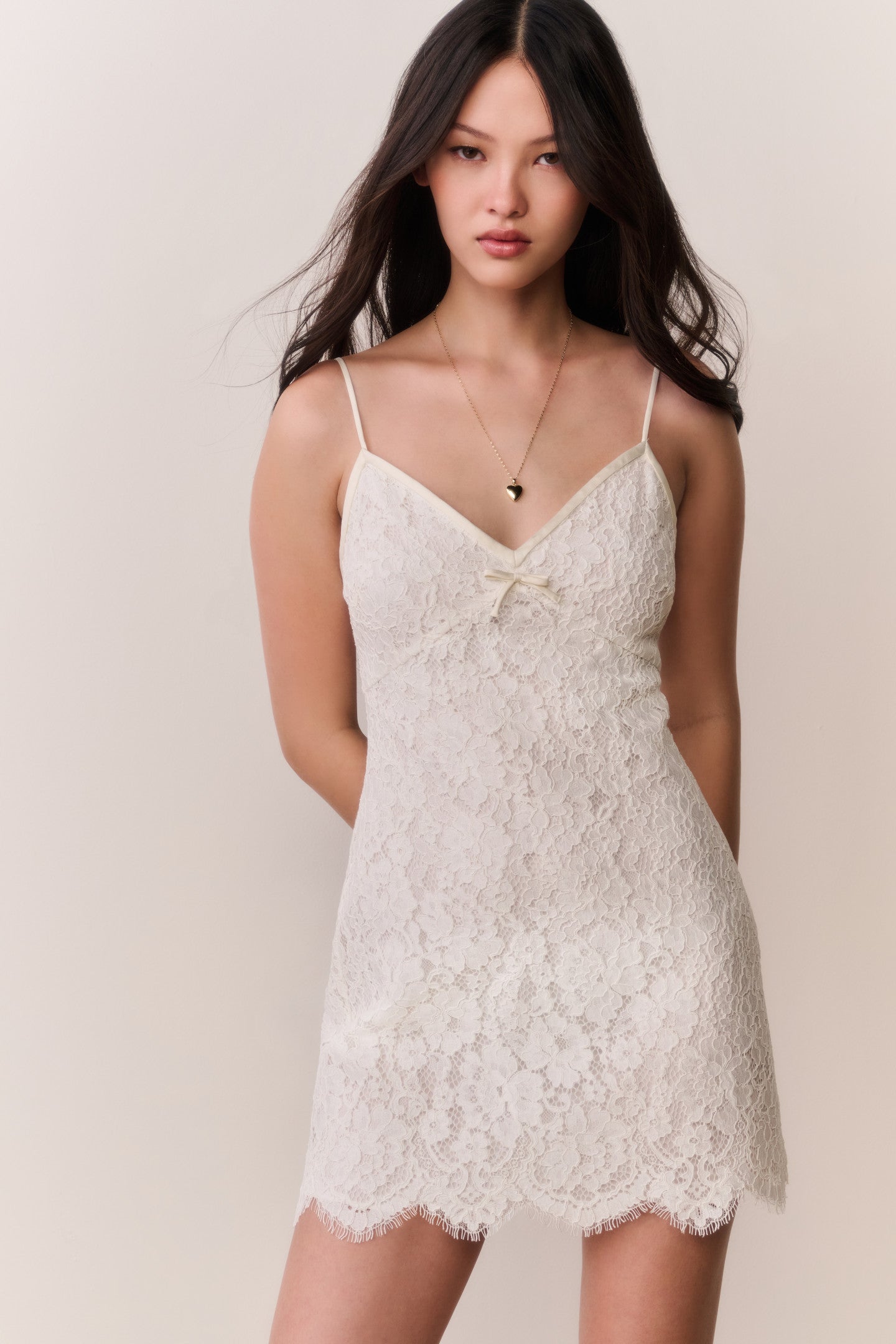 Woman wearing a white lace dress against a plain background