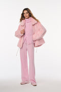Woman wearing a pink outfit with a matching coat on a white background