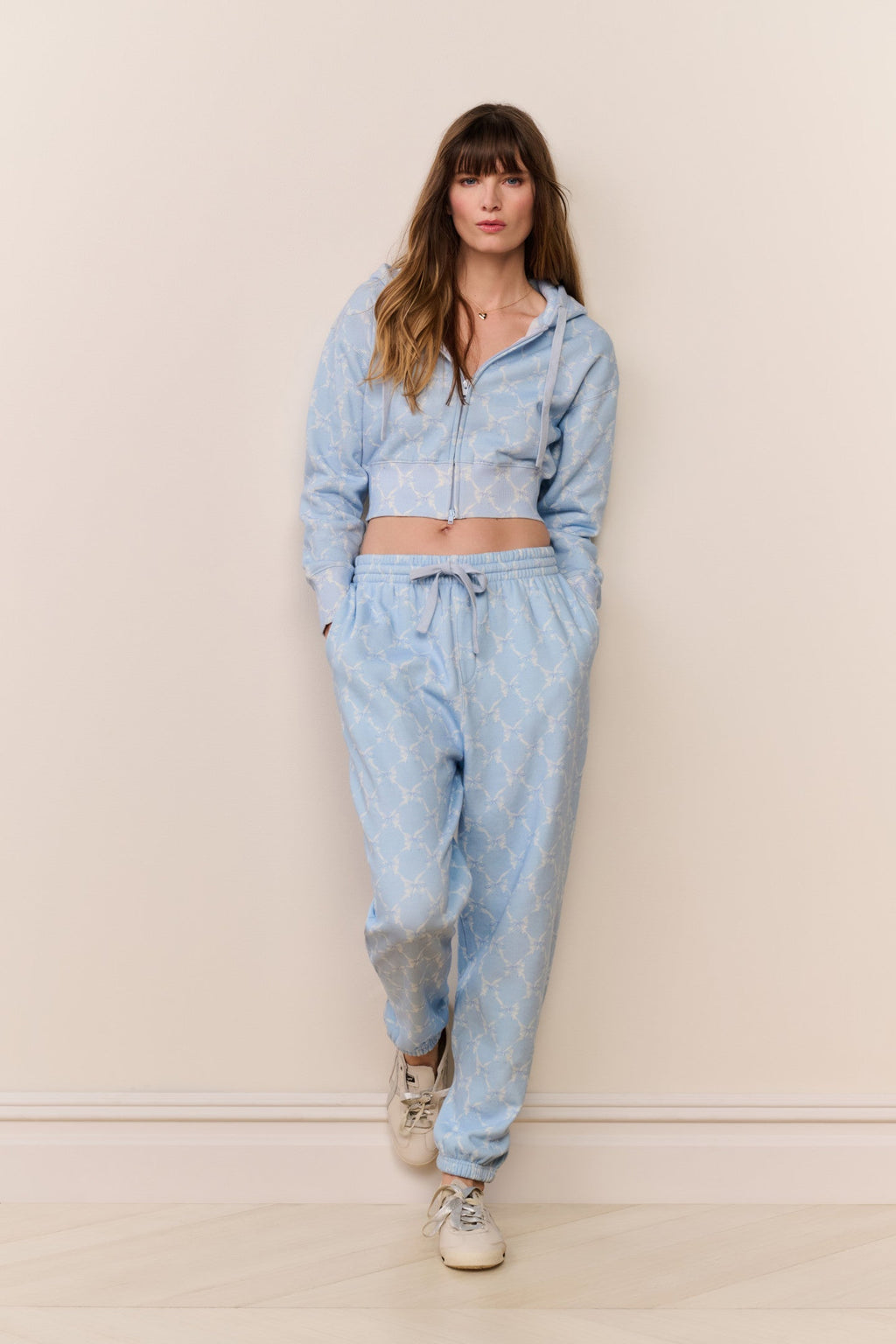 Woman wearing a light blue denim outfit against a beige background